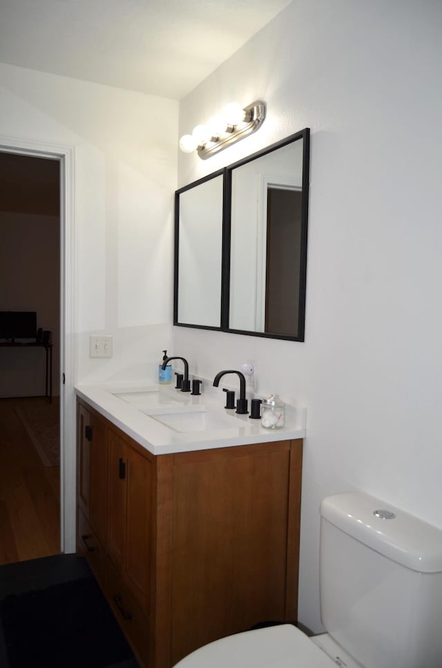 bathroom with toilet, vanity, and hardwood / wood-style floors