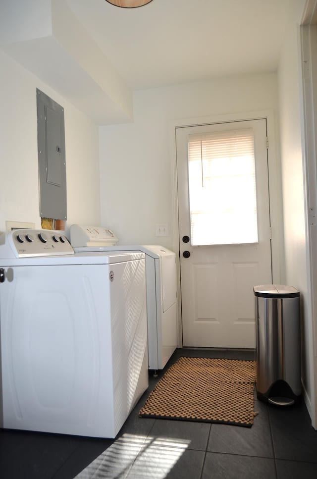 washroom with electric panel, washer and dryer, and dark tile patterned floors