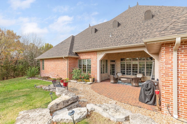 rear view of house with a lawn and a patio