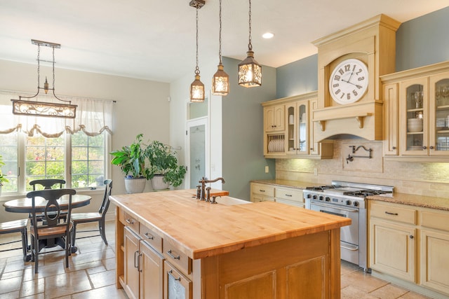 kitchen featuring sink, backsplash, an island with sink, high end stainless steel range, and wood counters