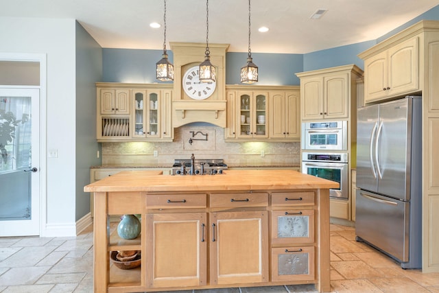 kitchen with butcher block counters, backsplash, appliances with stainless steel finishes, light brown cabinets, and pendant lighting