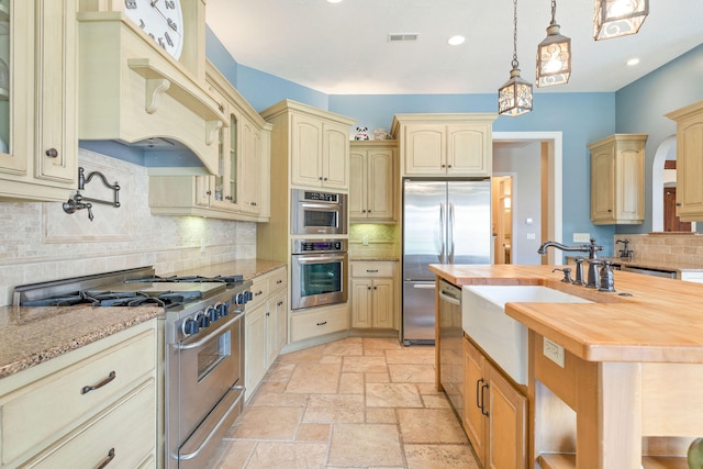 kitchen featuring stainless steel appliances, tasteful backsplash, wooden counters, custom exhaust hood, and hanging light fixtures