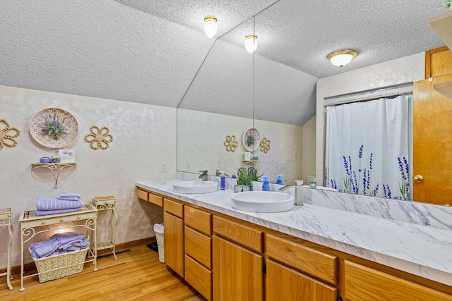 bathroom with hardwood / wood-style floors, vaulted ceiling, and vanity