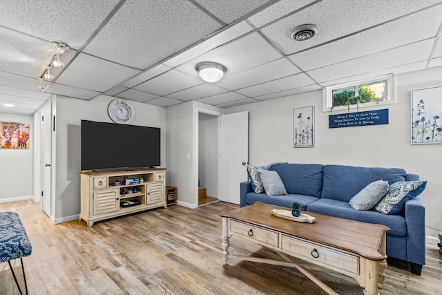 living room with a paneled ceiling and light hardwood / wood-style flooring