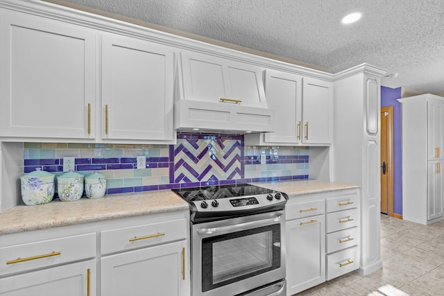 kitchen with a textured ceiling, white cabinets, backsplash, stainless steel electric range oven, and light tile patterned floors