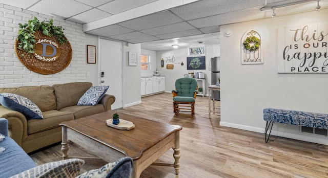 living room with a paneled ceiling and light hardwood / wood-style flooring