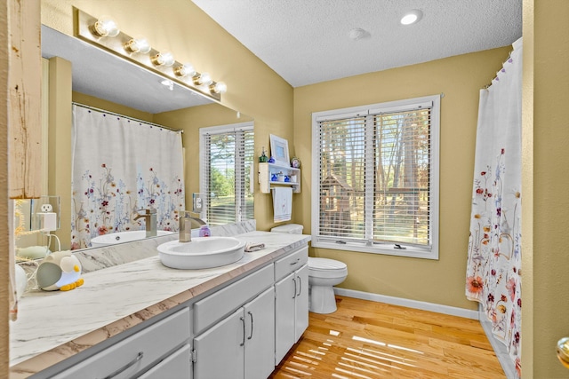 bathroom featuring wood-type flooring, toilet, a textured ceiling, and vanity