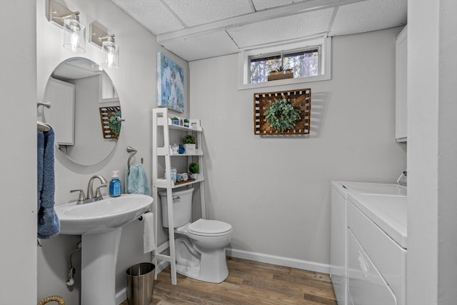 bathroom with toilet, hardwood / wood-style flooring, a drop ceiling, and washer and clothes dryer