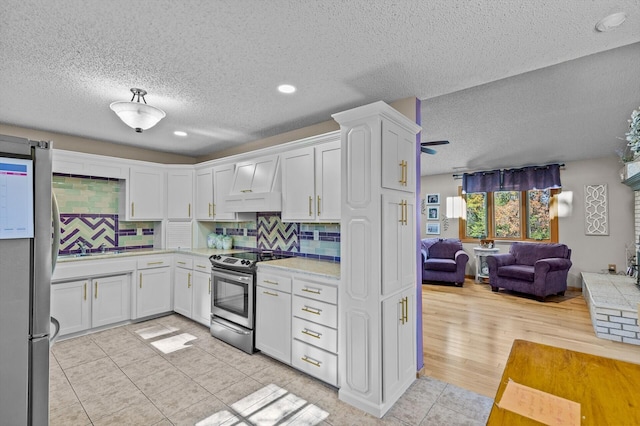 kitchen with stainless steel appliances, white cabinetry, custom range hood, and decorative backsplash