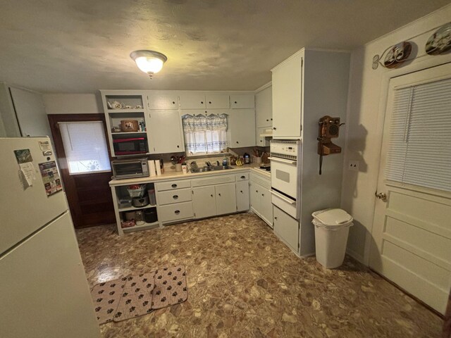 kitchen featuring white appliances, sink, and white cabinets