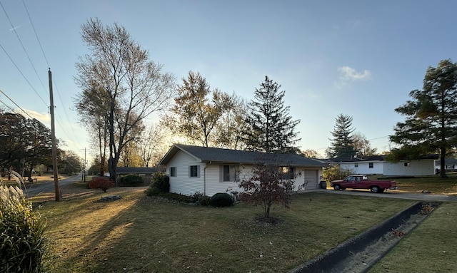 ranch-style house with a garage and a lawn