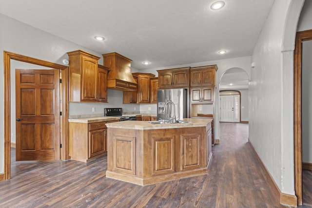 kitchen featuring sink, black electric range oven, dark hardwood / wood-style floors, premium range hood, and a kitchen island with sink