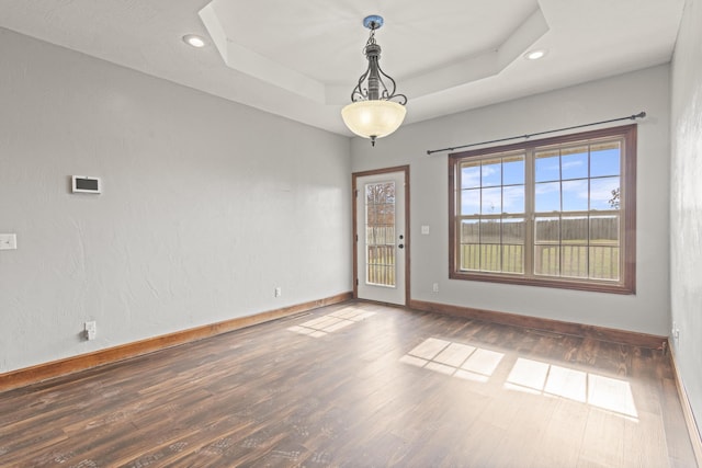 empty room with a tray ceiling and dark wood-type flooring