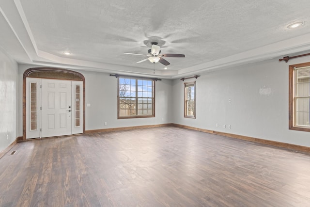 spare room featuring hardwood / wood-style floors, ceiling fan, a textured ceiling, and a tray ceiling