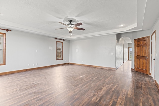 unfurnished room featuring ceiling fan, dark hardwood / wood-style flooring, a textured ceiling, and a tray ceiling