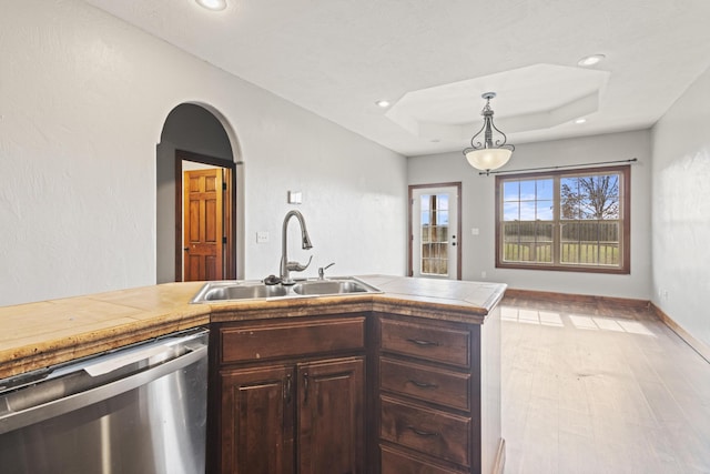 kitchen featuring sink, hanging light fixtures, light hardwood / wood-style flooring, stainless steel dishwasher, and dark brown cabinetry