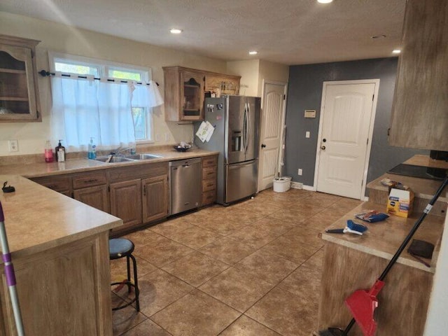 kitchen featuring a textured ceiling, sink, a breakfast bar area, light tile patterned flooring, and appliances with stainless steel finishes