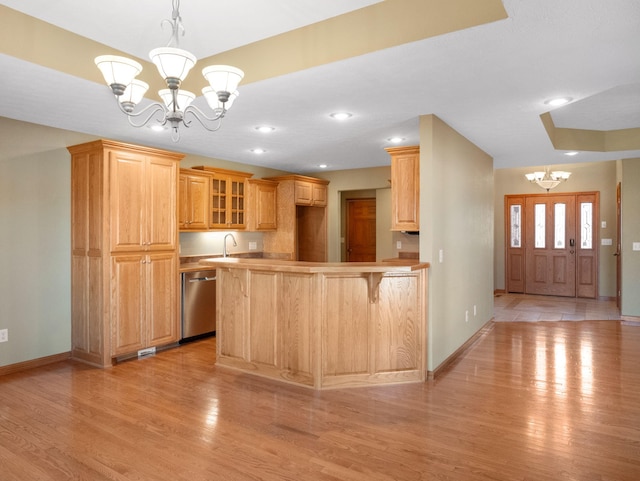 kitchen featuring kitchen peninsula, light wood-type flooring, dishwasher, and a notable chandelier