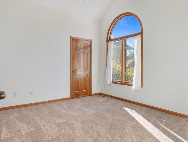 unfurnished room featuring a healthy amount of sunlight, carpet flooring, and vaulted ceiling