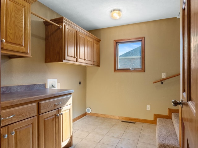 washroom featuring hookup for a washing machine, cabinets, light tile patterned flooring, and hookup for an electric dryer