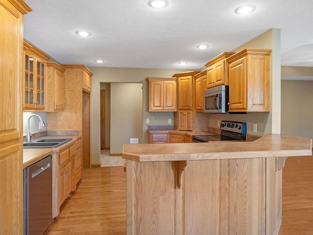 kitchen featuring kitchen peninsula, sink, a kitchen breakfast bar, and stainless steel appliances