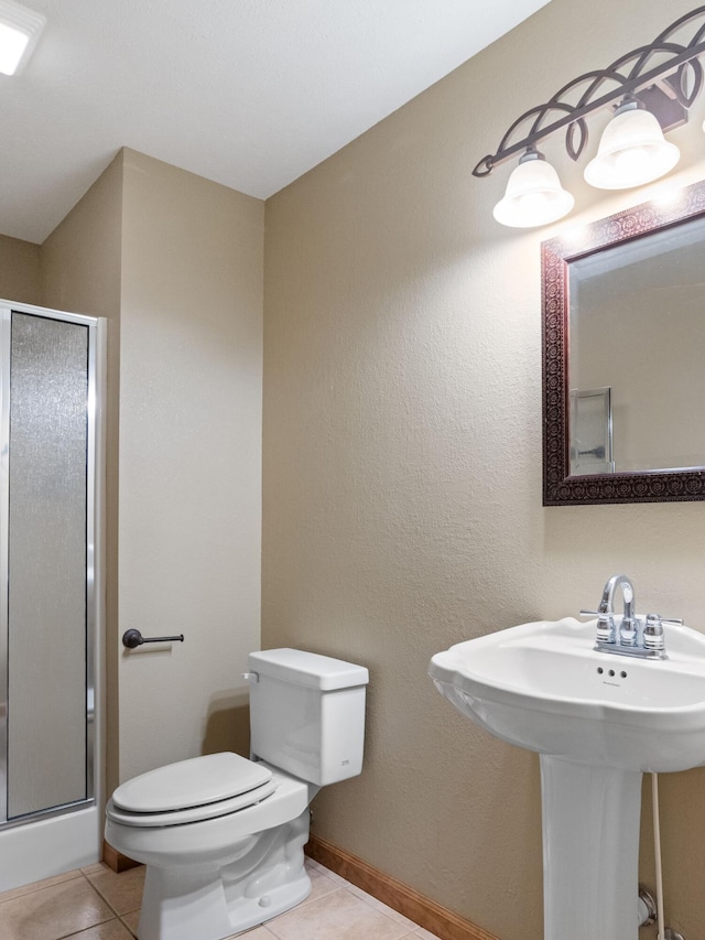 bathroom with tile patterned flooring, an enclosed shower, sink, and toilet