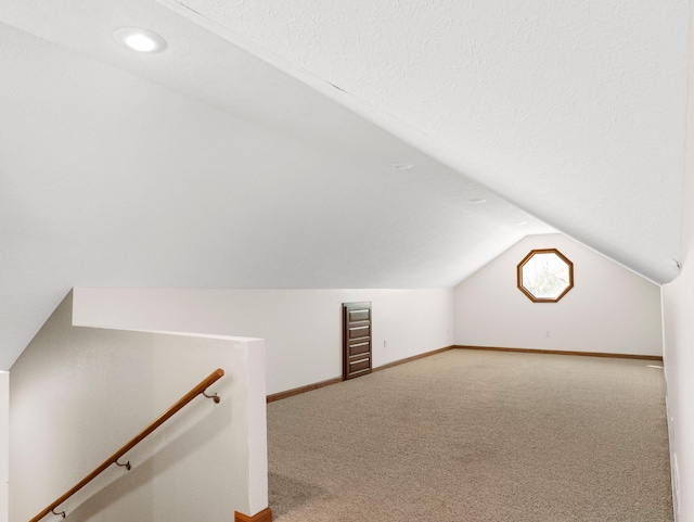 additional living space with vaulted ceiling, carpet flooring, and a textured ceiling