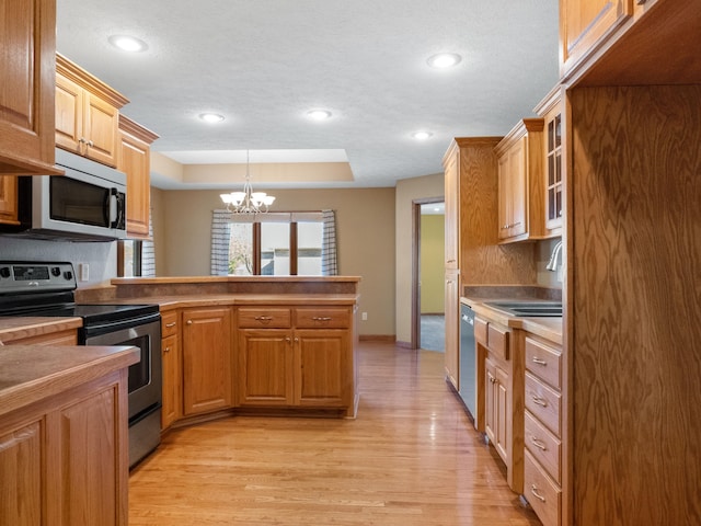 kitchen with stainless steel appliances, light hardwood / wood-style floors, sink, an inviting chandelier, and decorative light fixtures