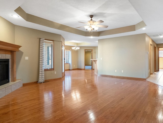 unfurnished living room with a fireplace, light wood-type flooring, and a raised ceiling