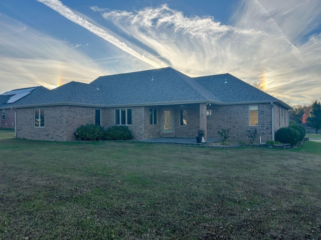 back house at dusk with a yard and a patio area