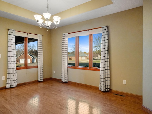 spare room featuring light hardwood / wood-style flooring and a notable chandelier