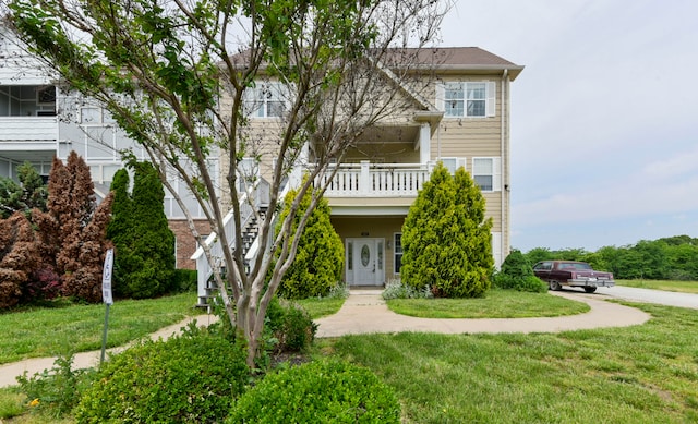 view of front facade with a front yard, french doors, and a balcony