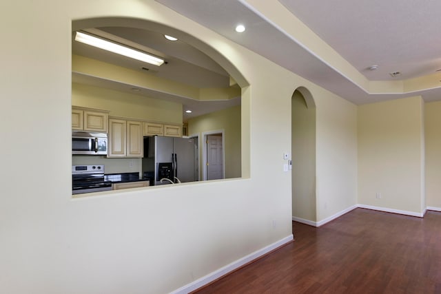 kitchen with appliances with stainless steel finishes, cream cabinetry, and dark hardwood / wood-style flooring