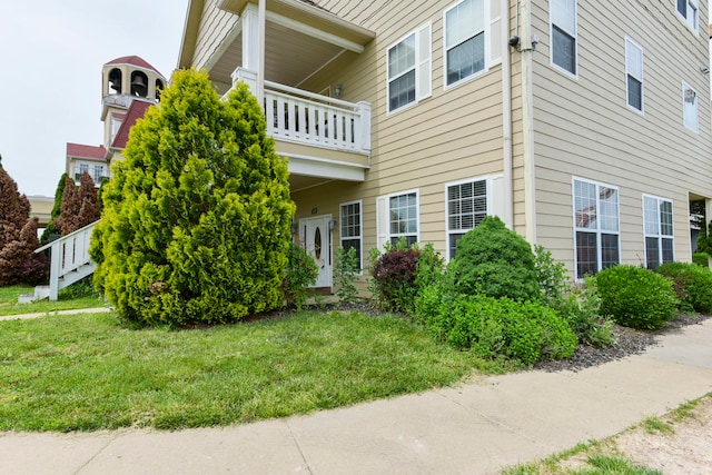 exterior space featuring a front lawn and a balcony