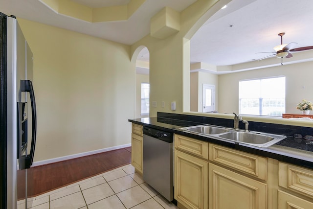 kitchen featuring appliances with stainless steel finishes, sink, light hardwood / wood-style floors, a tray ceiling, and ceiling fan