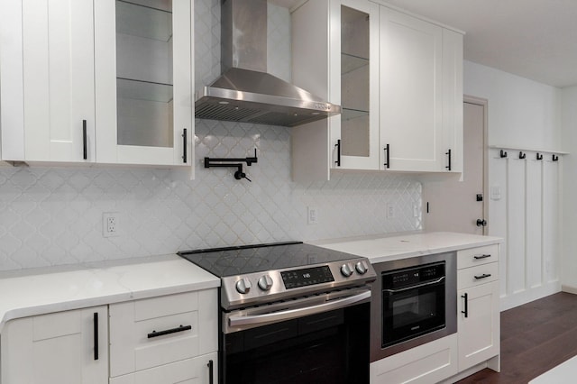 kitchen featuring dark wood-type flooring, wall chimney exhaust hood, white cabinetry, and stainless steel range with electric cooktop