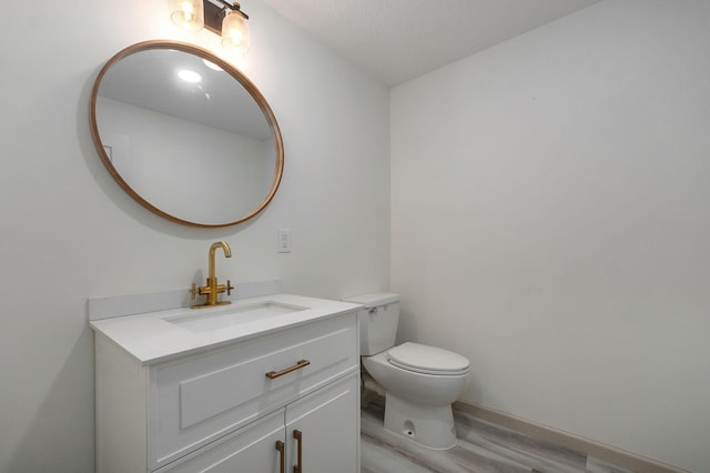 bathroom with toilet, vanity, and hardwood / wood-style floors