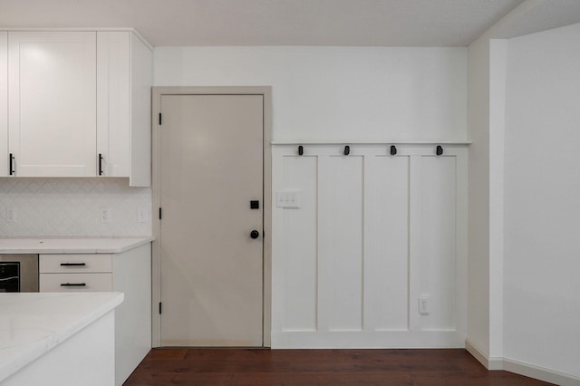 interior space with white cabinets, light stone countertops, dark wood-type flooring, and decorative backsplash