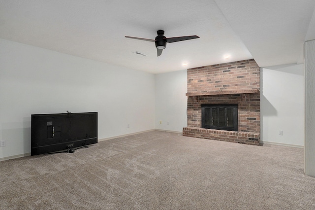 unfurnished living room featuring a brick fireplace, ceiling fan, and carpet flooring