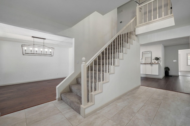 stairs with wood-type flooring and a notable chandelier