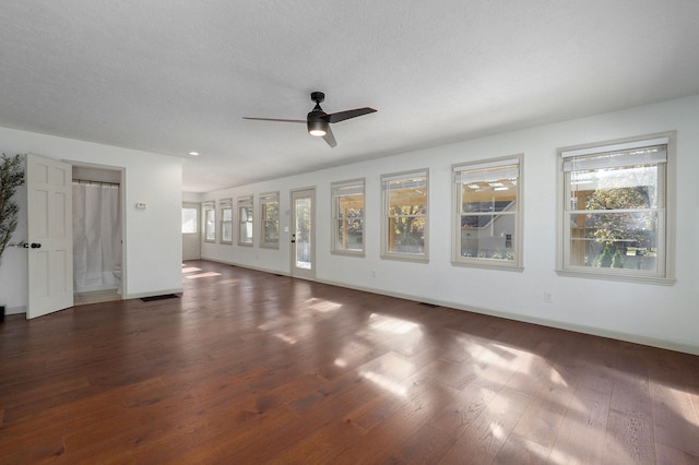 unfurnished living room with dark wood-type flooring, a textured ceiling, and ceiling fan