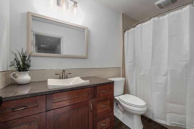 bathroom featuring tile walls, vanity, and toilet