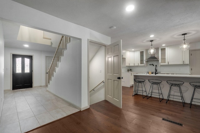 kitchen with white cabinetry, light wood-type flooring, a kitchen bar, hanging light fixtures, and kitchen peninsula