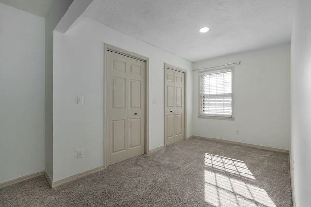 unfurnished bedroom featuring light colored carpet and a textured ceiling