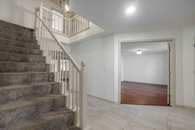 stairway featuring wood-type flooring and an inviting chandelier