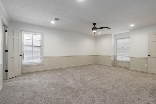 empty room featuring a textured ceiling, light colored carpet, and ceiling fan