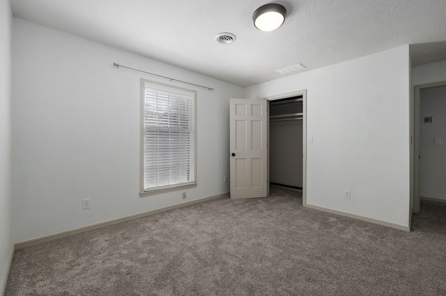 unfurnished bedroom featuring a textured ceiling, a closet, and carpet