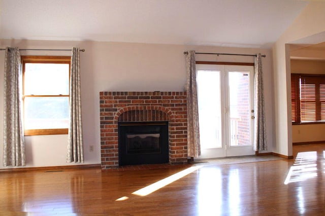 unfurnished living room with a fireplace, hardwood / wood-style floors, and lofted ceiling