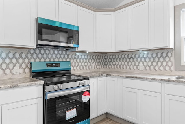 kitchen with white cabinetry, appliances with stainless steel finishes, and tasteful backsplash