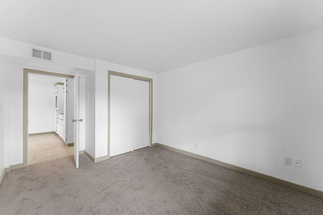 unfurnished bedroom featuring light carpet and a closet